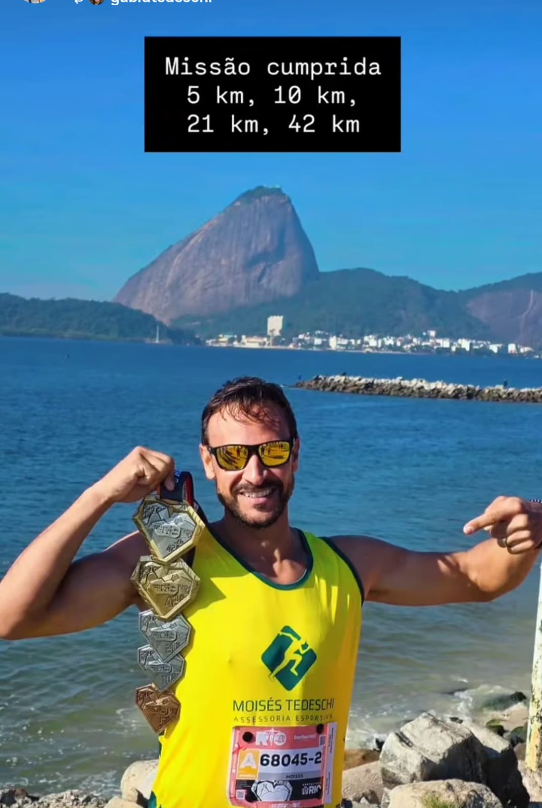 Moisés Tedeschi exibindo medalhas de 5km, 10km, 21km e 42km, com o Pão de Açúcar ao fundo